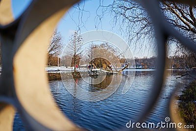 Park view trough a railing of a bridge over a lake. Stock Photo