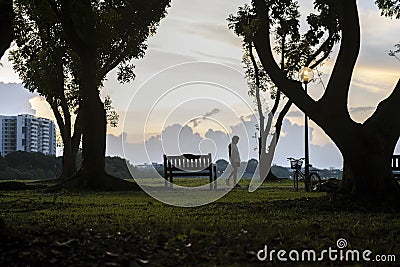 A park visitor stroll slowly with head looking down at Bedok Reservoir park during evening sunset. Editorial Stock Photo