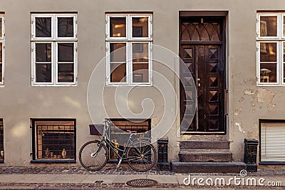 parked bicycle with basket near grey building with closed doors on street Stock Photo