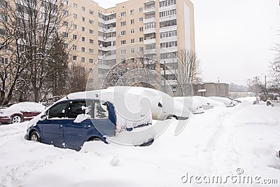 Parked cars, covered in snow, stand along the road. Snowfall in the city, falling snowflakes. Concept: traffic collapse, increased Stock Photo