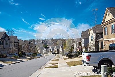 Parked cars at front garage along residential street leading down a steep hill in new development suburban neighborhood suburbs Stock Photo