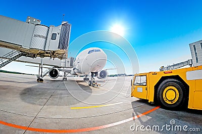Parking at the airport, airplane at the teletrap. Aerodrome tractor is ready for towing and departure of the aircraft. Against the Stock Photo