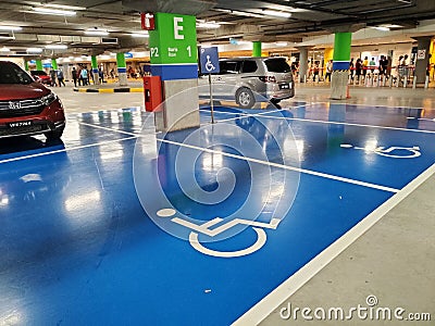 Parking for the disabled. The parking lot has a blue background and has a special logo. Editorial Stock Photo