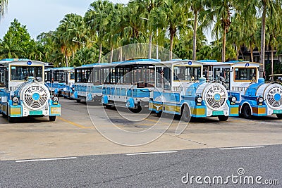 Parking with fun vehicles in the form of a blue steam locomotives for carries tourists and visitors on the territory of Buddhist Editorial Stock Photo