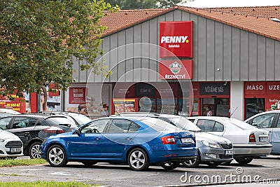 A parking lot with many colourful cars with blue Skoda Octavia in front of the shop of the Penny Market supermarket chain in Czech Editorial Stock Photo