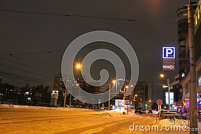 Parking sign neon light at night over dark sky arrow illuminated by lanterns. night street in winter Editorial Stock Photo