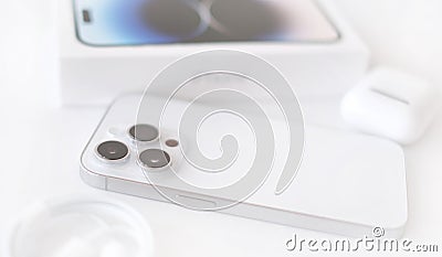 Isolated on white background new IPhone 14 pro in silver color with a triple camera, box and a wire to charge the device Editorial Stock Photo