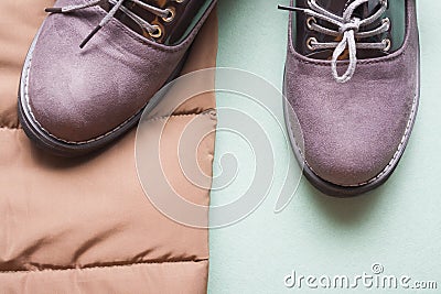Part of brown autumn jacket and purple autumn pair of boots on light green background with copy space. Stock Photo
