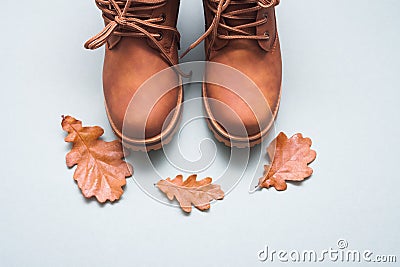 Part of brown autumn pair of boots on gray background with autumn oak leaves with copy space Stock Photo