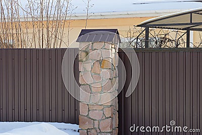 Part of a brown wall of a fence made of stones and metal Stock Photo