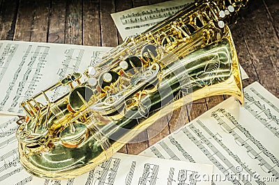 part of the case tube with pockets and bells of a yellow saxophone and letters with sheet music on an old wooden surface Stock Photo