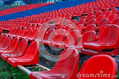 Grandstand of an old football stadium with plastic red and blue seats Stock Photo