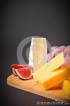Part of Cheeseboard platter with hard and soft mould cheese, grape and segmented fig on wooden board Stock Photo
