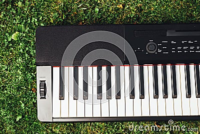 Part of electric piano keyboard, green grass background Stock Photo