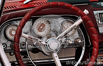 Part of the interior of an oldtimer luxury car with steering wheel, speedometer, fuel, clock dials, gear lever, front panel Stock Photo