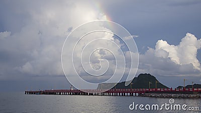 A part of Rainbow with blue sky and cloud over Red long bridge and the sea, mountain in background, peace wave Stock Photo