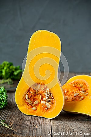 Part of ripe orange pumkin with seeds stading on the rustic wooden table on the dark grey stone background. Vegetarian, healthy di Stock Photo