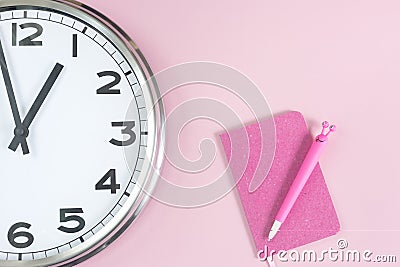 Part of wall clock with pink notepad and pen Stock Photo