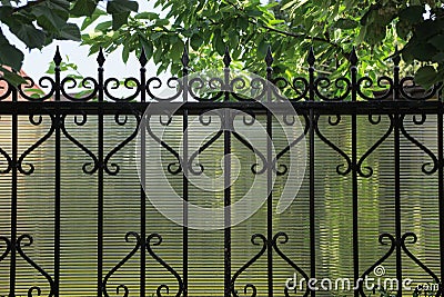 Part of the wall of a fence made of sharp black iron rods in a forged pattern Stock Photo