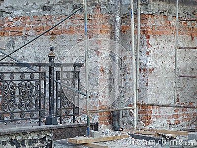 Part of the wall of an old building. Crumbling brickwork surrounded by construction debris. Stock Photo
