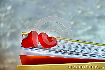 Partial blur Two red hearts on the pages of a book, retro noise effect of contrasting enhanced colors, love in valentine`s day Stock Photo