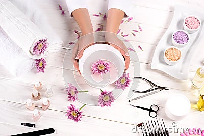 partial image of woman holding bath for nails over table with flowers, towels, colorful sea salt, aroma oil bottles, nail Stock Photo