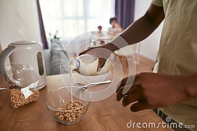 Partial of man pouring milk in bowl with cereals Stock Photo