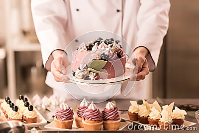 partial view of confectioner holding cake in hands Stock Photo