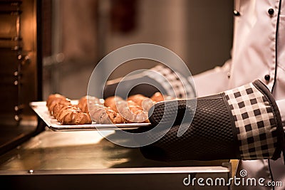 partial view of confectioner taking eclairs on baking pan out Stock Photo
