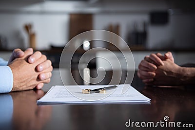 View of couple sitting at table with clenched hands near divorce documents Stock Photo