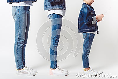 partial view of family and kid with tablet in similar denim clothing standing in row Stock Photo