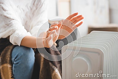 View of girl warming up with heater in cold room Stock Photo