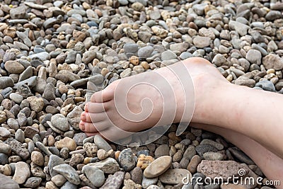 Partial view of a human bare foot on pebbles Stock Photo