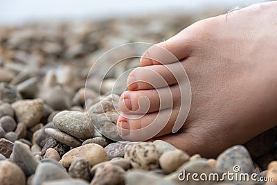 Partial view of a human bare foot on pebbles Stock Photo