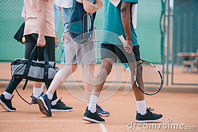 partial view of multicultural elderly men with tennis equipment walking Stock Photo