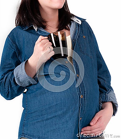 Woman in blue denim shirt holding dark glass cup with tea and touching belly isolated on white Stock Photo