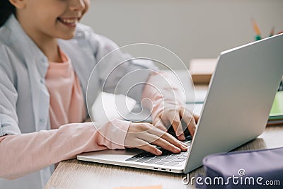 View of smiling schoolkid using laptop while doing schoolwork at home Stock Photo