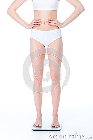 Partial view of young slim woman with hands on waist standing on digital scales Stock Photo
