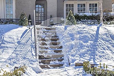 Partially cleared steps in snowy yard - concrete steps climb steeply uphill from street to house and look dangerous Stock Photo