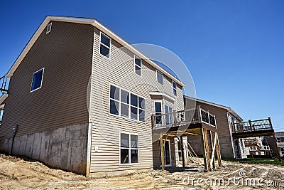 Partially finished new two-story homes under construction in subdivision with vinyl siding and windows installed and new deck Stock Photo