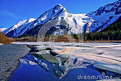 A Partially Frozen Lake with Mountain Range Reflected in the Partially Frozen Waters of a Lake in the Great Alaskan Wilderness. Stock Photo