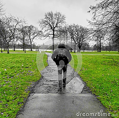 Partially grayscale shot of a young male walking in a park with green grass Stock Photo