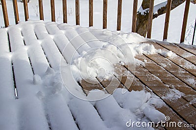Partially shoveled snow designs on a wooden deck Stock Photo