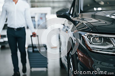 Partical view. Man in formal clothes is with luggage indoors near the car Stock Photo