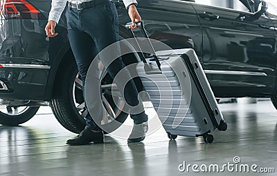 Partical view. Man in formal clothes is with luggage indoors near the car Stock Photo