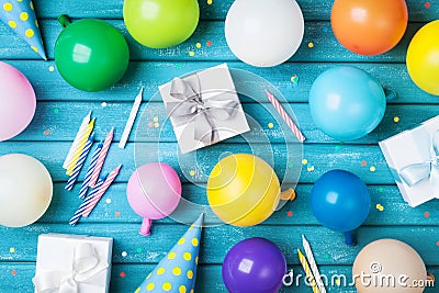 Party birthday table. Colorful balloons, gifts, confetti and carnival cap on blue table top view. Holiday supply. Stock Photo