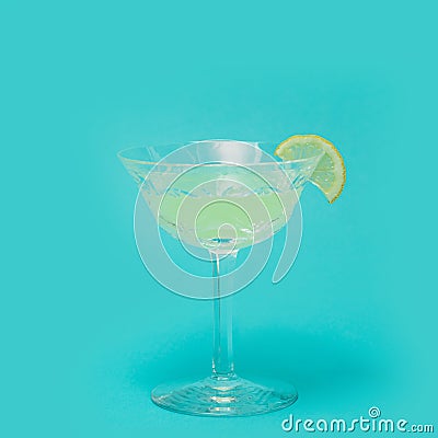 Party concept made of unique, luxurious crystal glass with yellow cocktail with lemon attached. Lovely blue background Stock Photo