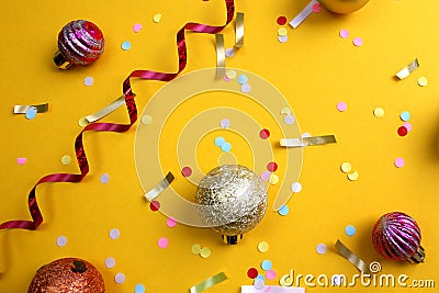 On a yellow background lies a swirling ribbon, festive confetti and balls Stock Photo