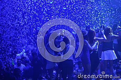Party at disco with young people on the stage with blue lights and confetti rains. Editorial Stock Photo