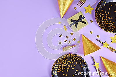 Party flat lay with black and golden plates, forks, gift, champagne bottle and star confetti on violet background Stock Photo